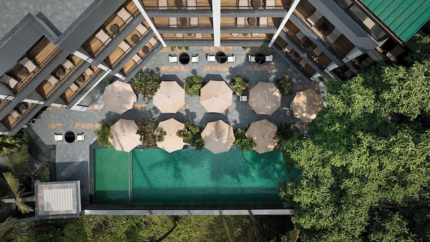 An aerial view of a hotel courtyard with outdoor seating, a swimming pool, and surrounding greenery. - Spark by Hilton Goa Calangute (Calangute)