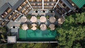 An aerial view of a hotel courtyard with outdoor seating, a swimming pool, and surrounding greenery. - Spark by Hilton Goa Calangute (Calangute)