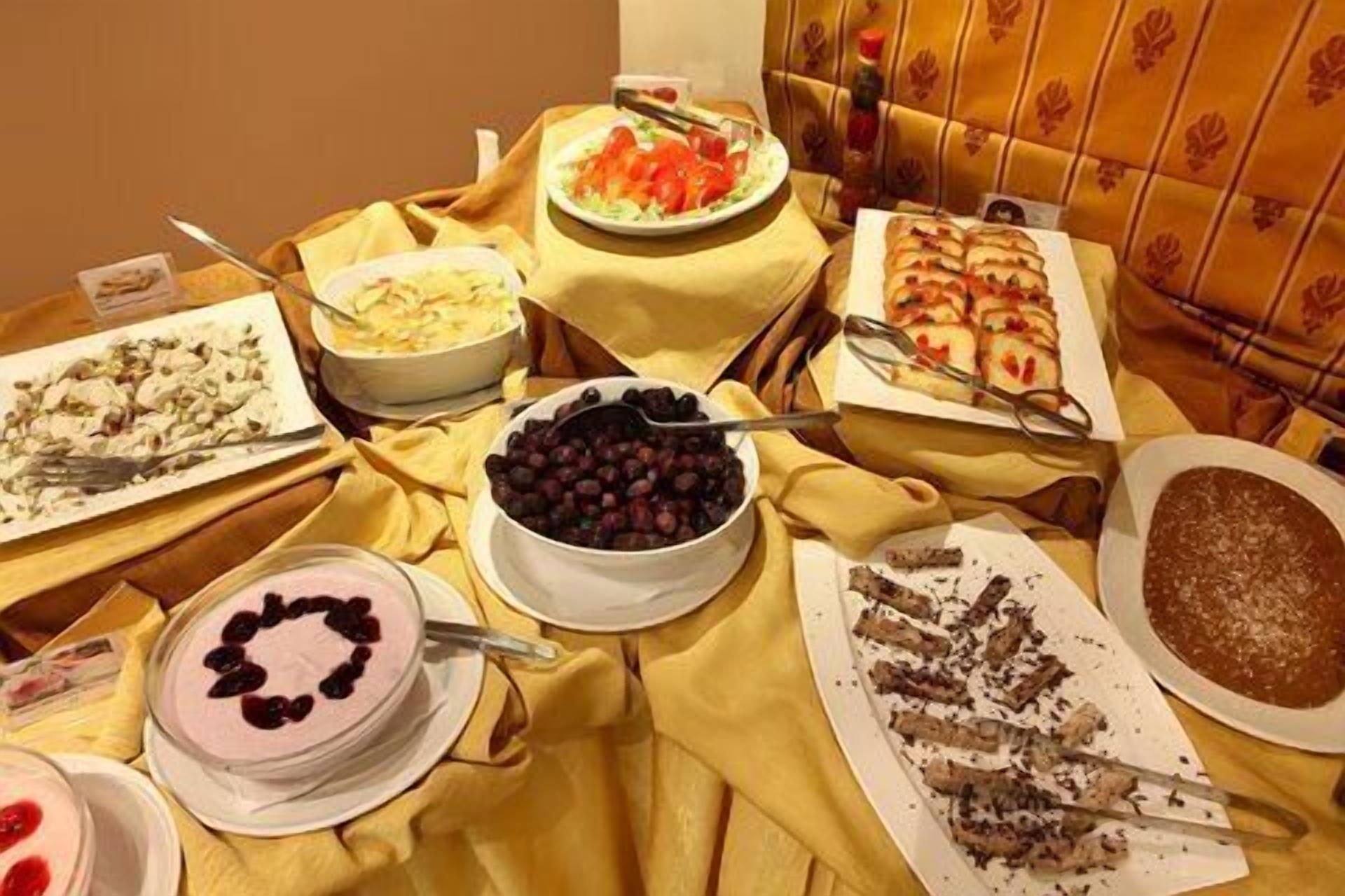 A table with various dishes including a cake, a bowl of cherries, and a plate of sliced meat.