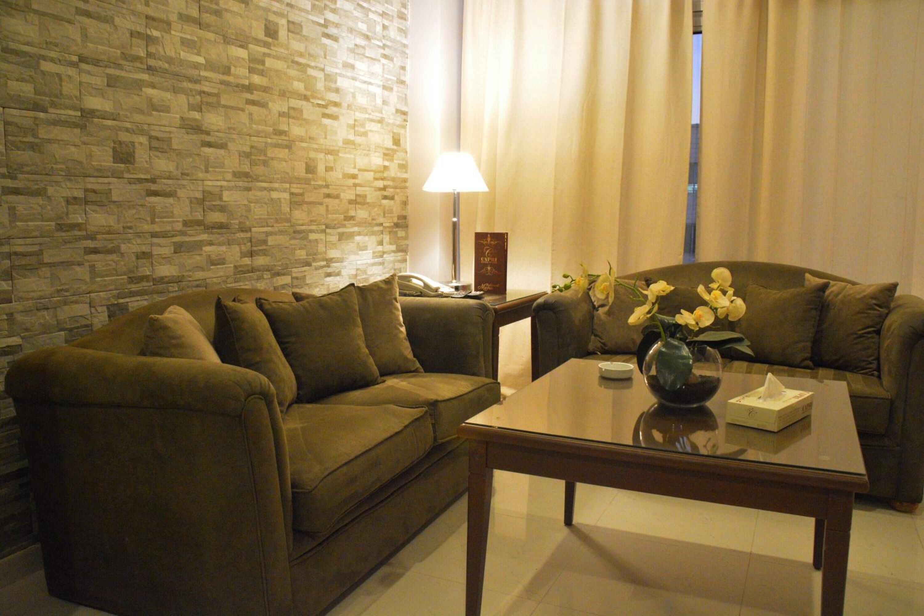 A living room with two sofas, a coffee table, a lamp, and a vase with flowers.