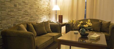 A living room with two sofas, a coffee table, a lamp, and a vase with flowers.