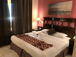 Una cama bien hecha con una colcha estampada, una almohada decorativa y una toalla sobre la cama.