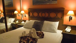A hotel room with a neatly made bed, two wall-mounted lamps, a nightstand with a phone, and a painting on the wall. - Capri Hotel Suites (Amman)