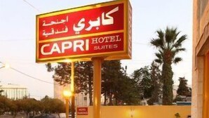 A hotel exterior with outdoor seating, tables set for dining, and a sign indicating "CAPRI HOTEL SUITES". - Capri Hotel Suites (Amman)