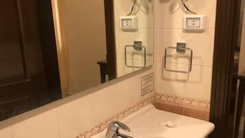 A bathroom with a sink, a mirror, and two hair dryers mounted on the wall.