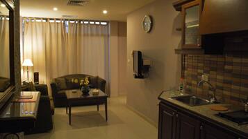 Un espacio habitable compacto con sofá, una mesita de centro y una zona de cocina que incluye un lavabo y armarios.