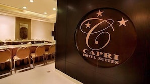 A conference room with a long table and chairs, and a wall with the logo and name of Capri Hotel Suites. - Capri Hotel Suites (Amman)