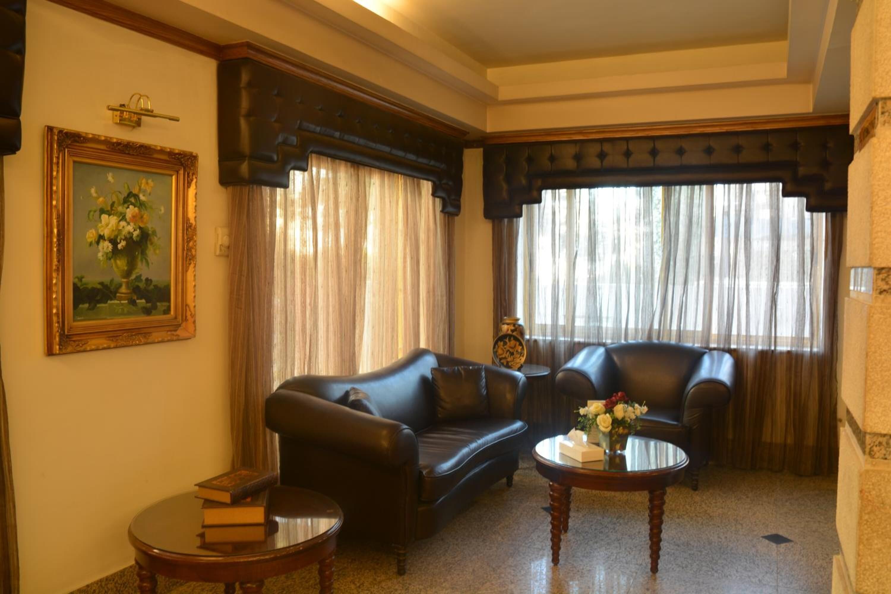 Ein Wohnzimmer mit einem dunklen Ledersofa, einem kleineren Sessel, einem runden Couchtisch und einem Gemälde an der Wand.