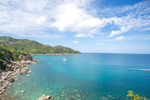 Un paisaje costero con aguas azul cristalino, costas rocosas y un telón de fondo montañoso.