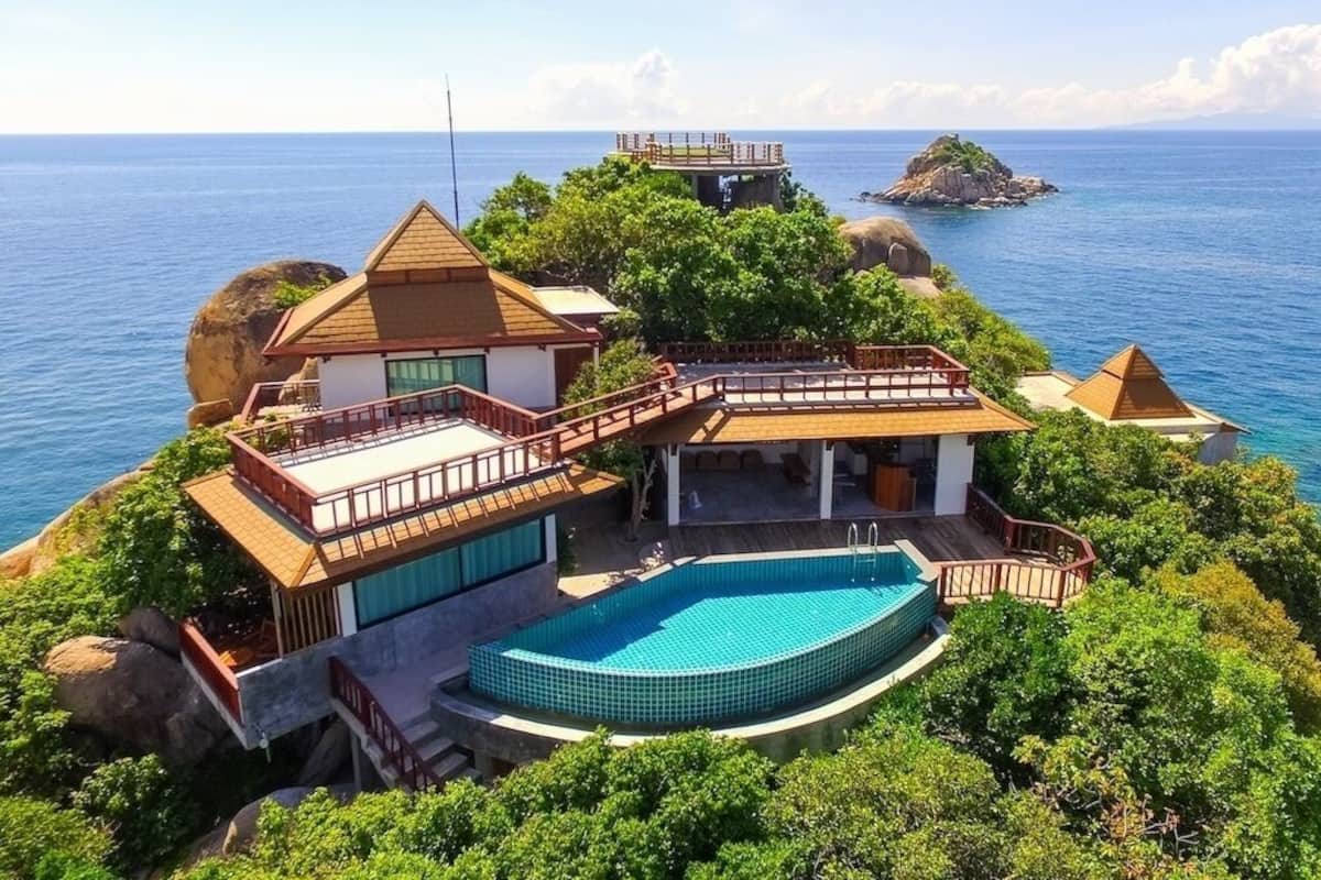 A beachfront property with a swimming pool, a covered patio, and a view of the ocean.