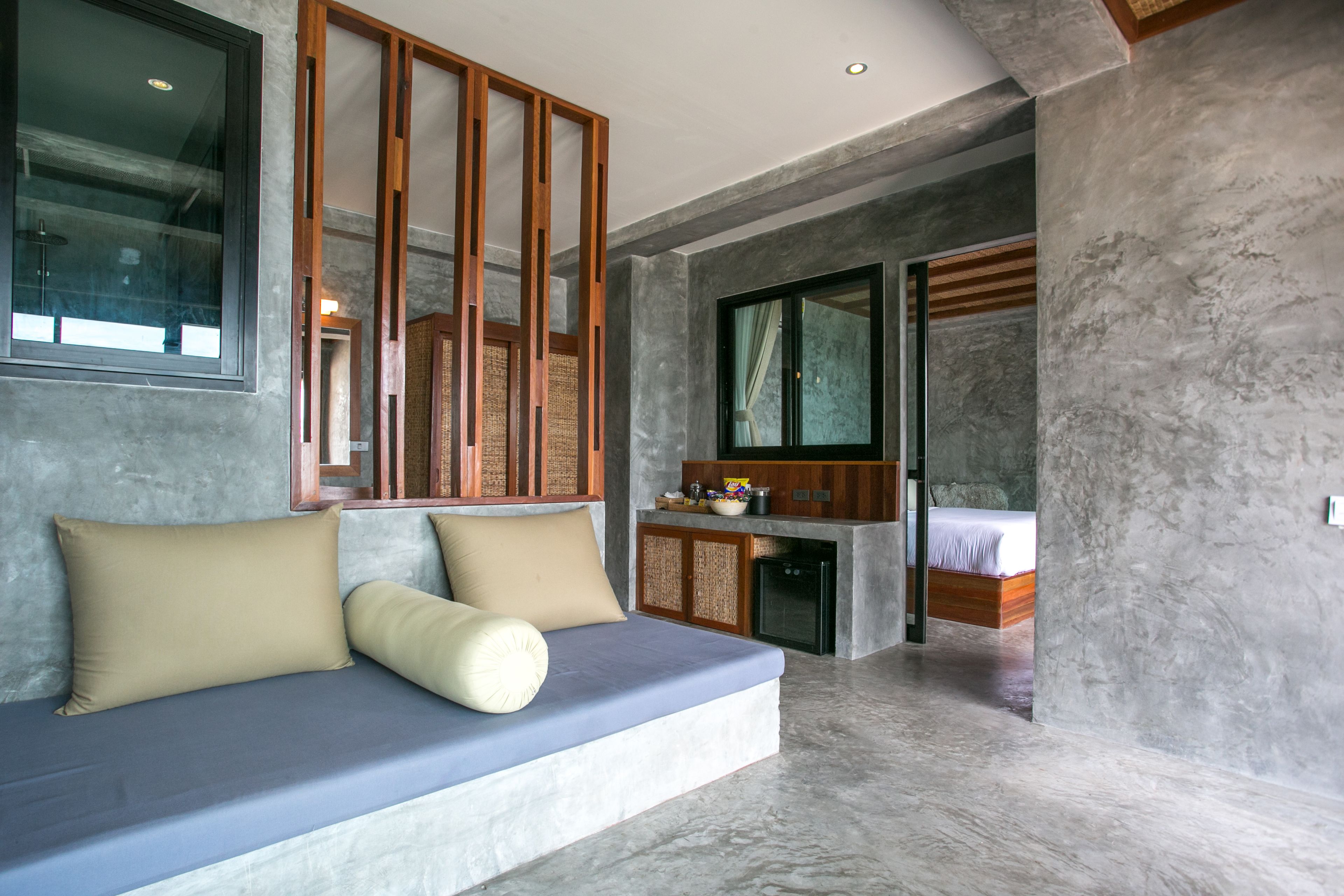 A modern room with a built-in sofa, a small kitchen area, and a separate sleeping area.