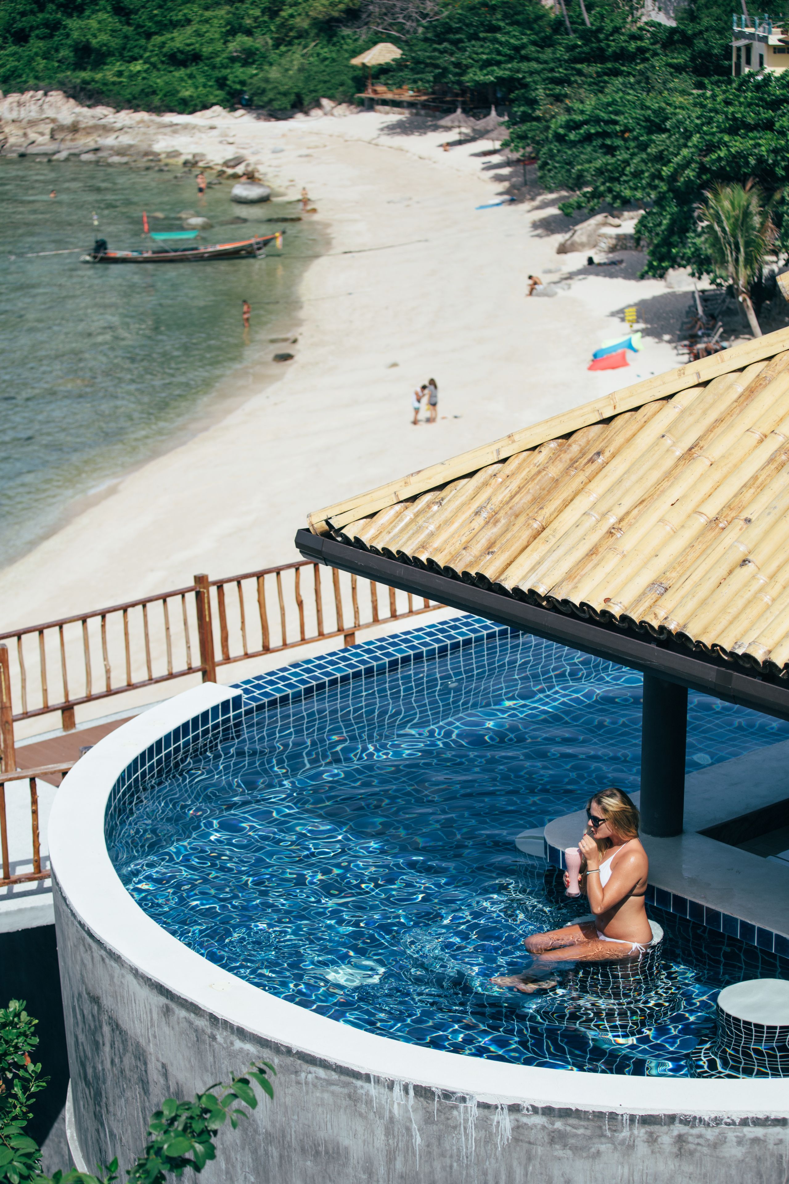 Un espace piscine avec vue sur une plage et une terrasse en bois.