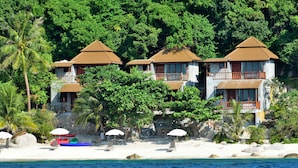 A beachfront property with multiple buildings, a sandy beach, and a palm tree. - Sai Daeng Resort (Koh Tao)