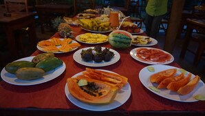 A table with various fruits and a watermelon on a red tablecloth. - Hotel Mango Garden (Kandy)