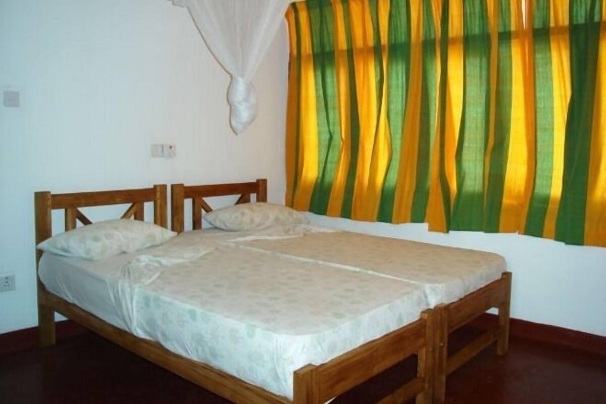 Una cama doble con estructura de madera, colchón y cubrecama blancos.