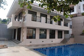 A two-story residential building with a swimming pool, balconies, and a staircase leading to the upper floor. - La Vida Studio Inn Baga - Goa By Lords Hotels & Resorts (Arpora)