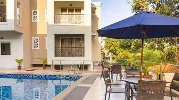 A poolside area with a pool, outdoor seating, and a building with balconies.
