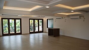A spacious room with large sliding glass doors leading to a balcony, recessed ceiling lighting, and an air conditioning unit on the wall.
