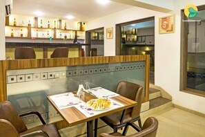 A restaurant with a bar area, a dining table with chairs, and a view of the bar through a glass partition. - La Vida Studio Inn Baga - Goa By Lords Hotels & Resorts (Arpora)