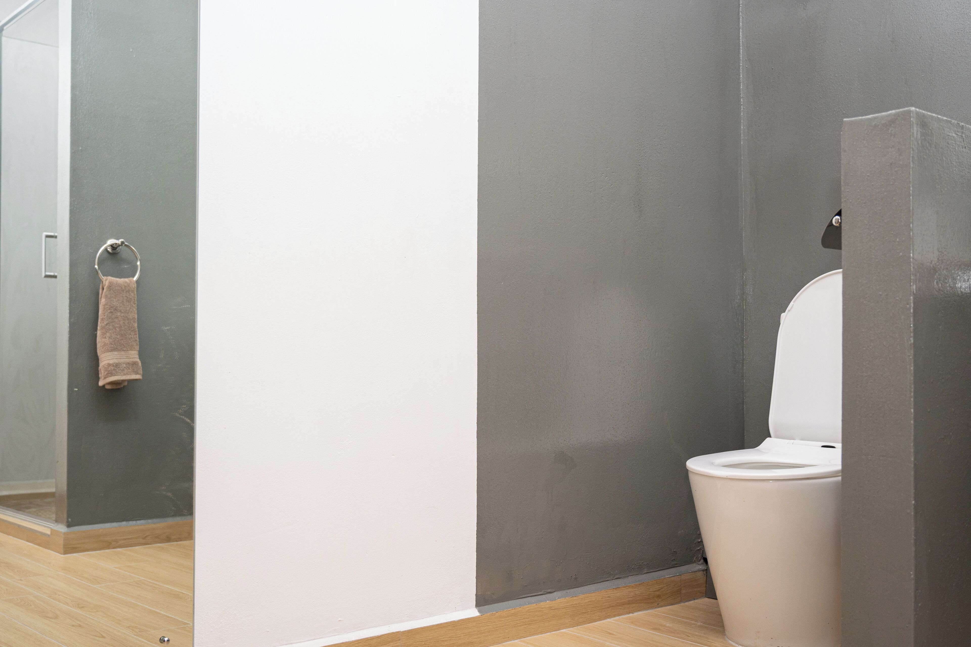 Ein Badezimmer mit Toilette, Handtuchhalter und Duschbereich.
