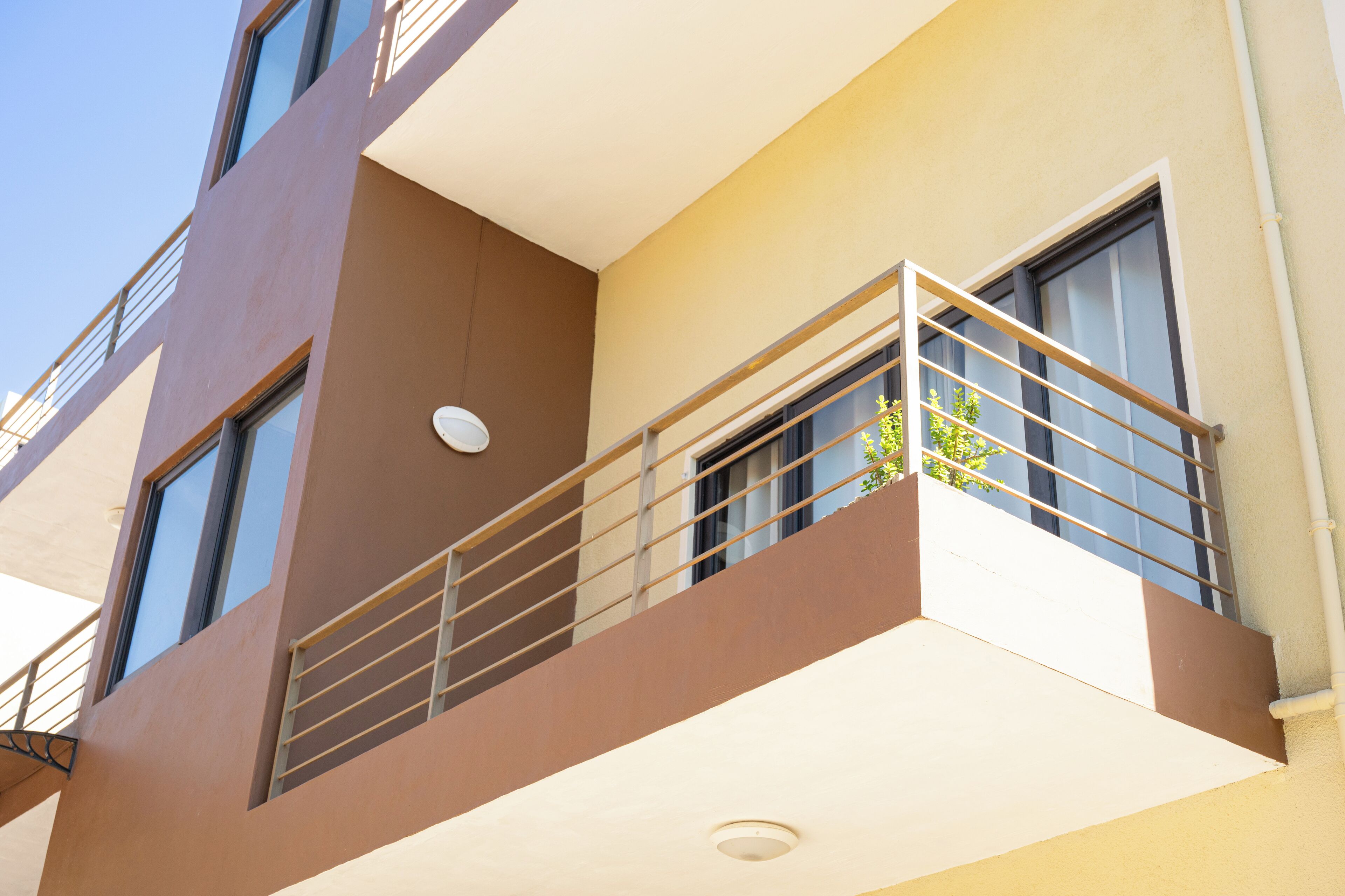 Un edificio de varios pisos con balcones, ventanas grandes y techo plano.
