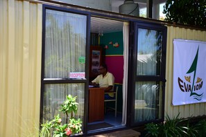 A reception area with a man seated at a desk, a reception sign, and a banner with the logo "EVA LION". - EvaZion (Grand River South East)