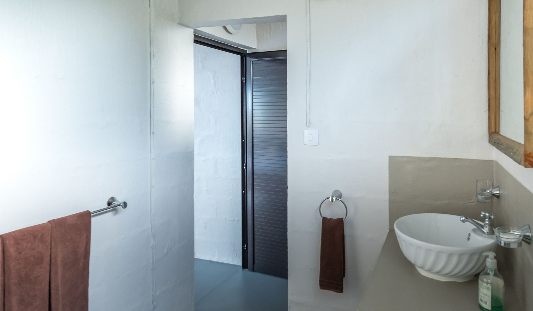 A modern bathroom with a white sink, a mirror, and a towel rack.