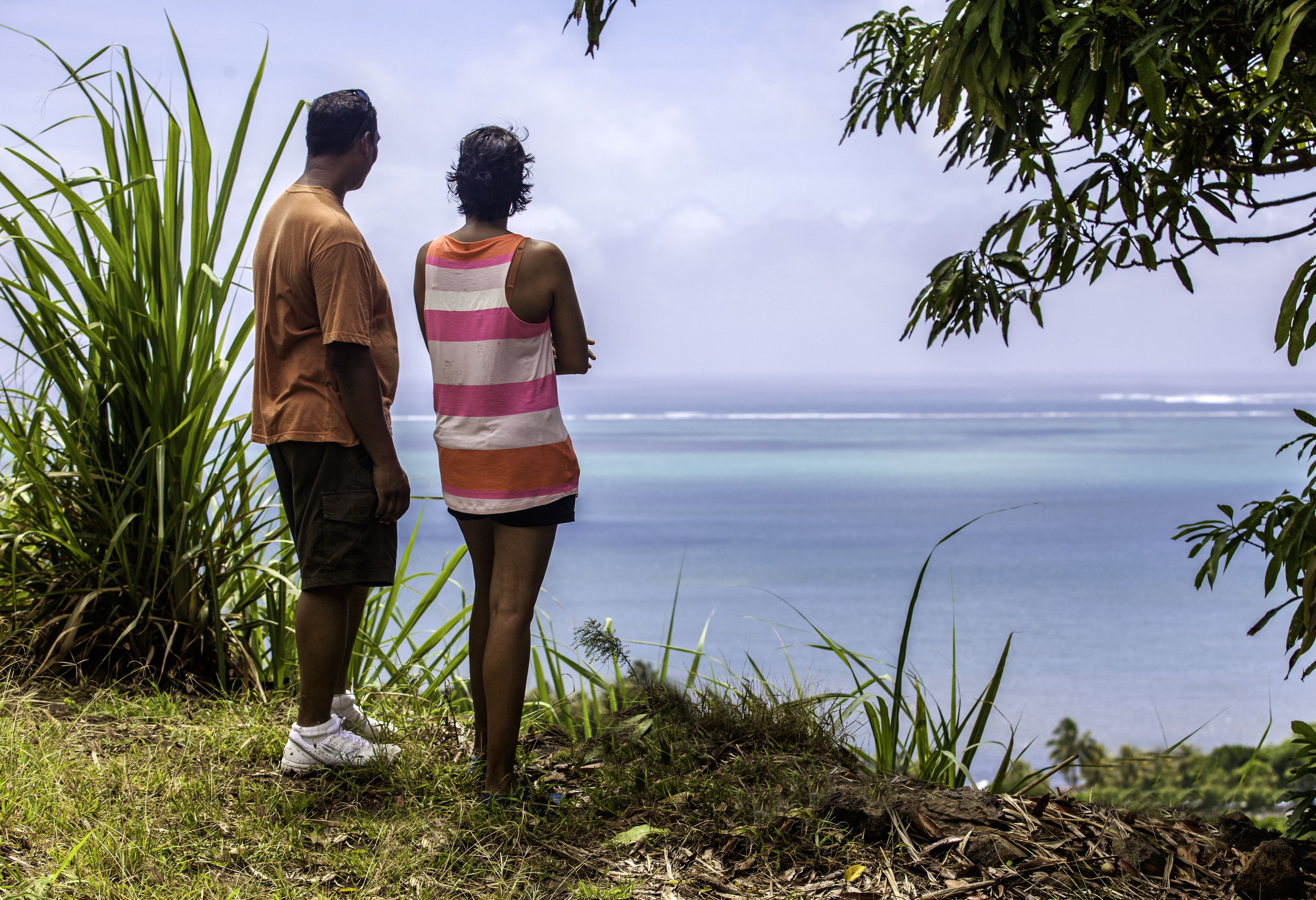 Two people standing on a grassy area overlooking a body of water.