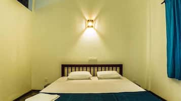 Uma cama de solteiro com cabeceira de madeira, roupa de cama branca e um cobertor azul.