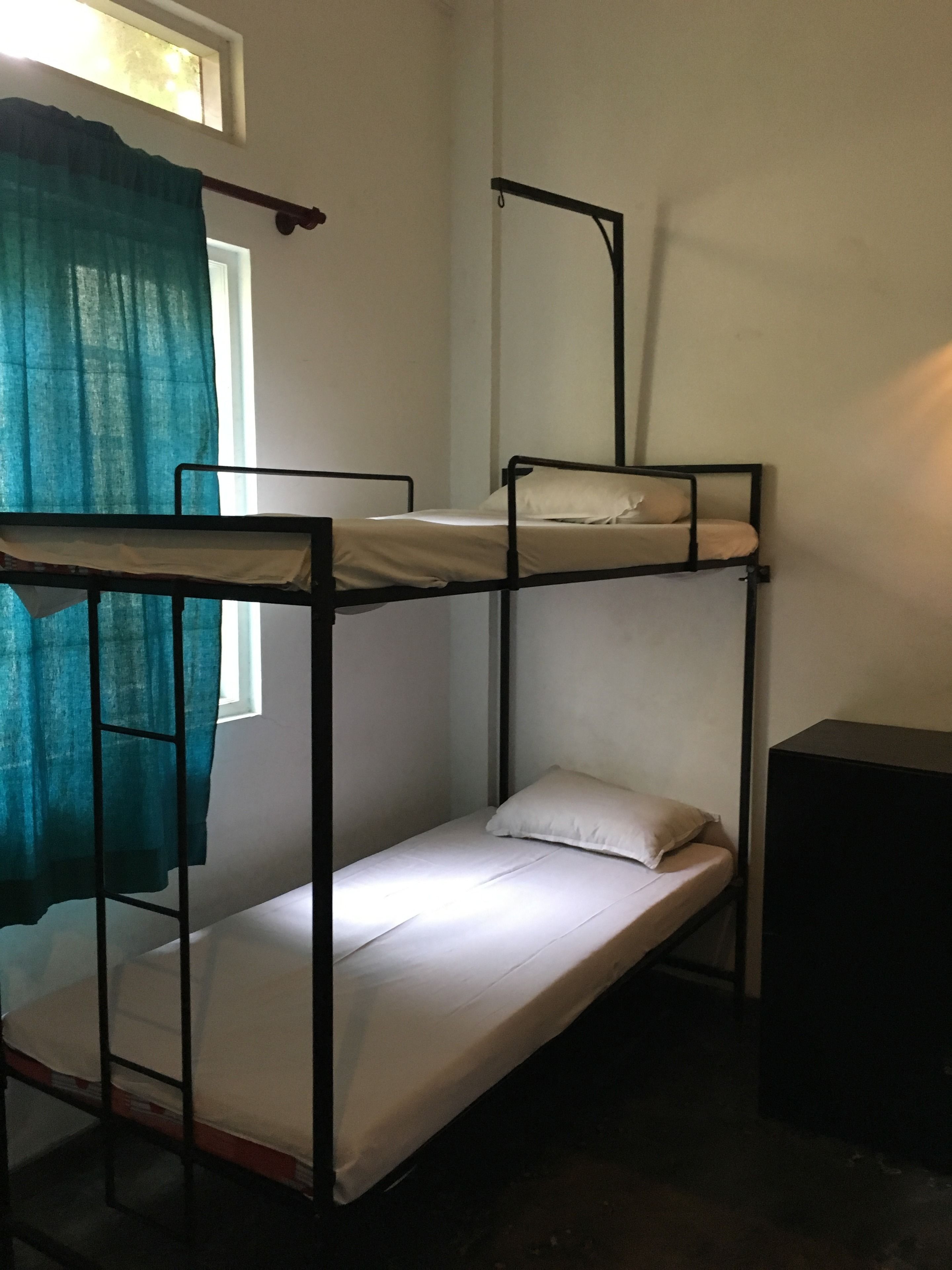A bunk bed room with a window and curtains.