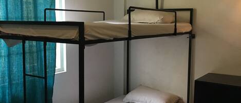 A bunk bed room with a window and curtains.