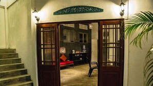 A staircase leading to a room with a red sofa, a chair, and a water dispenser. - Colombo Beach Hostel (Mount Lavinia)