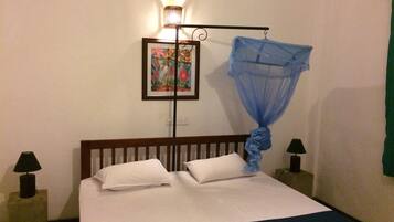 A hotel room with a bed, two bedside lamps, a wall-mounted picture, and a mosquito net.
