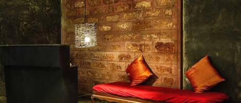 A room with a wooden bench, a black cabinet, and a patterned wall.