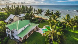 A large house with a green roof, a swimming pool, and a view of the ocean. - Ocean Beach Villa (Trou aux Biches)
