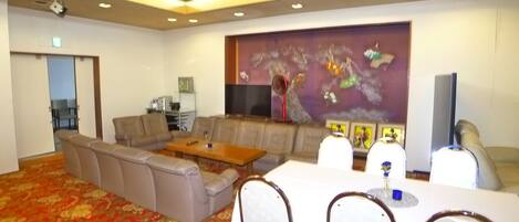 A conference room with a sectional sofa, a round table, and a large flat-screen TV.