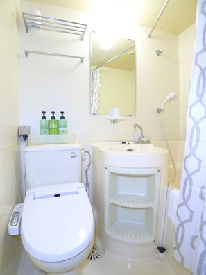 A compact bathroom with a toilet, sink, and shower. There are three bottles of soap on the sink counter. - New Makomo Hotel (Itako)