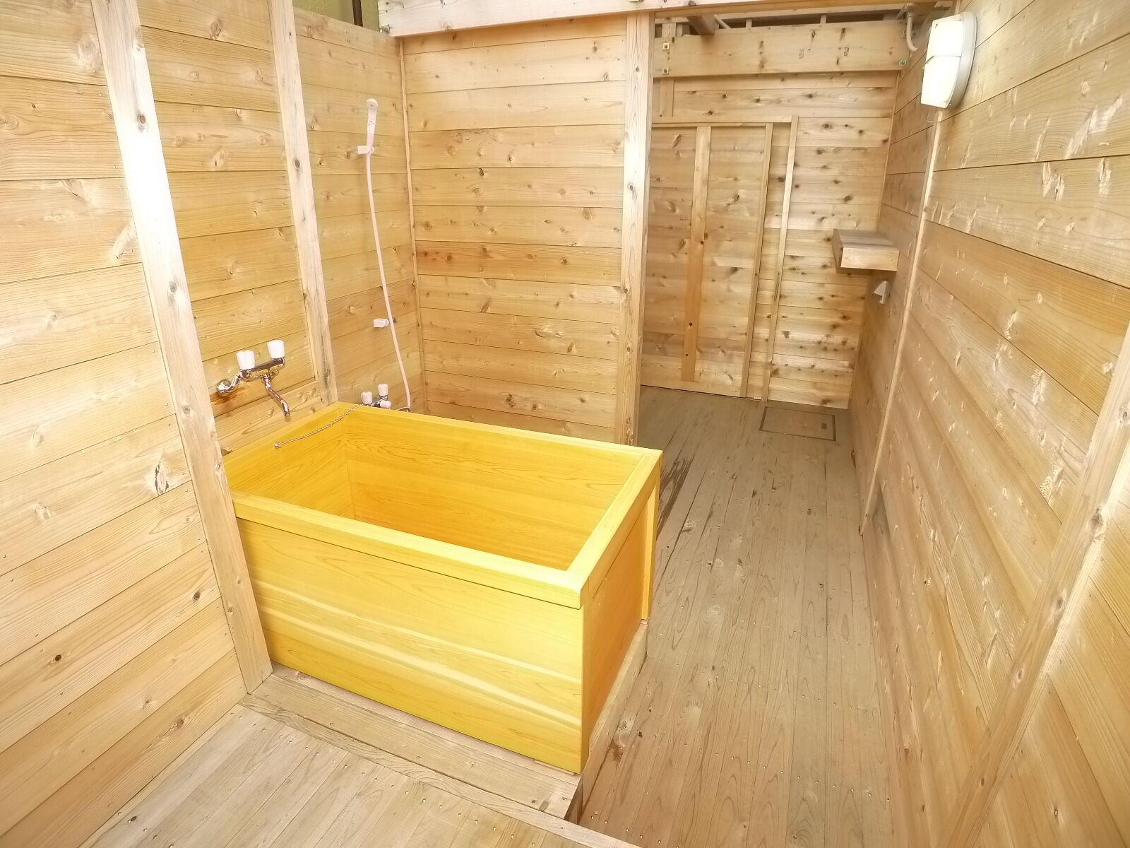 A wooden sauna with a rectangular wooden tub, wooden walls, and a wooden bench.