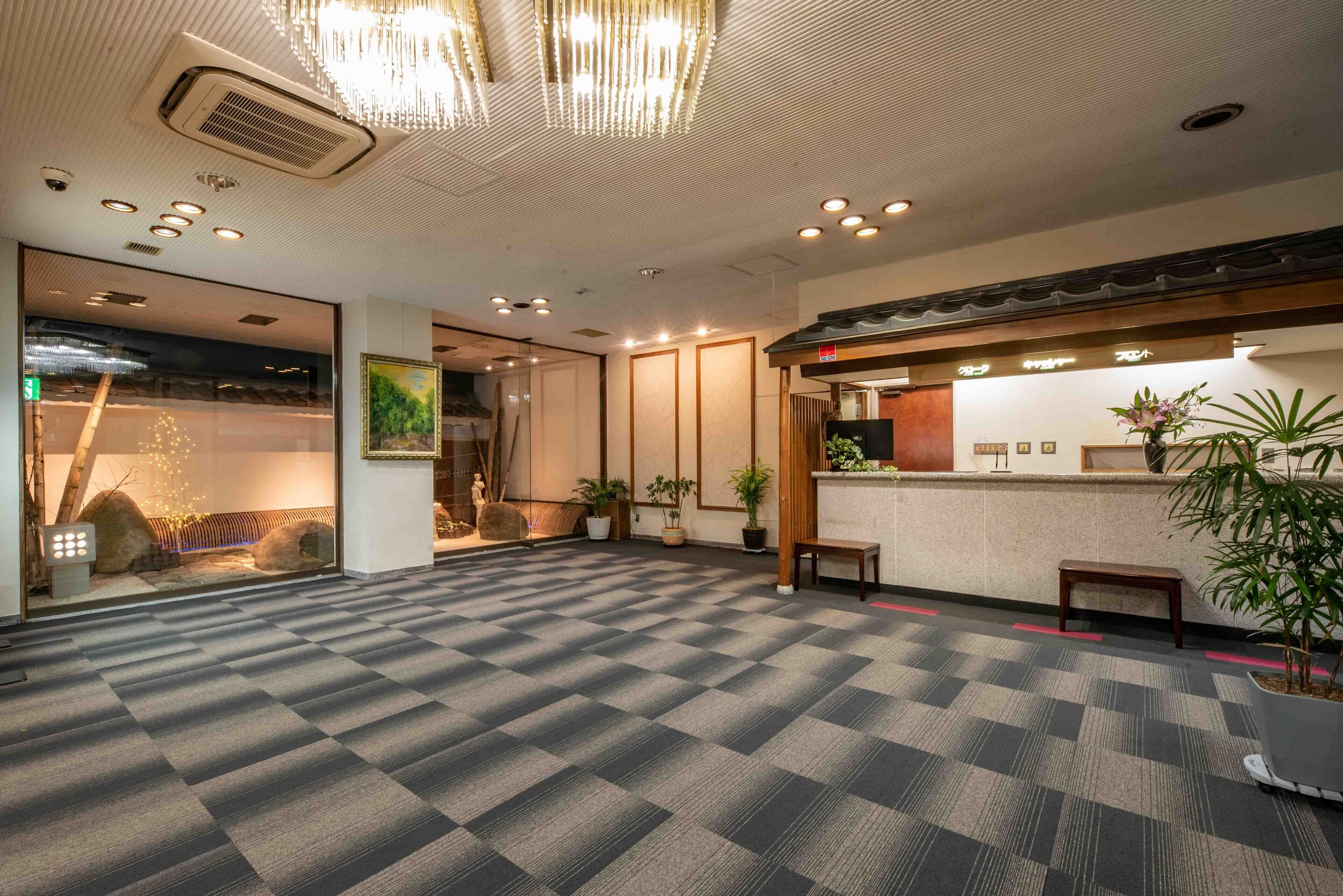 A spacious lobby with a checkered floor, a reception desk, and potted plants.