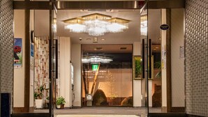 A hotel entrance with a modern design, featuring a glass door, a chandelier, and a sign indicating a parking area. - New Makomo Hotel (Itako)