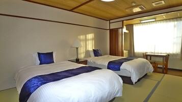 Habitación de hotel con dos camas, un escritorio y una silla.