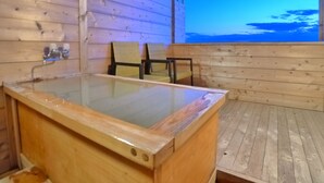 A wooden cabin with a glass-enclosed hot tub, wooden flooring, and two wicker chairs. - New Makomo Hotel (Itako)