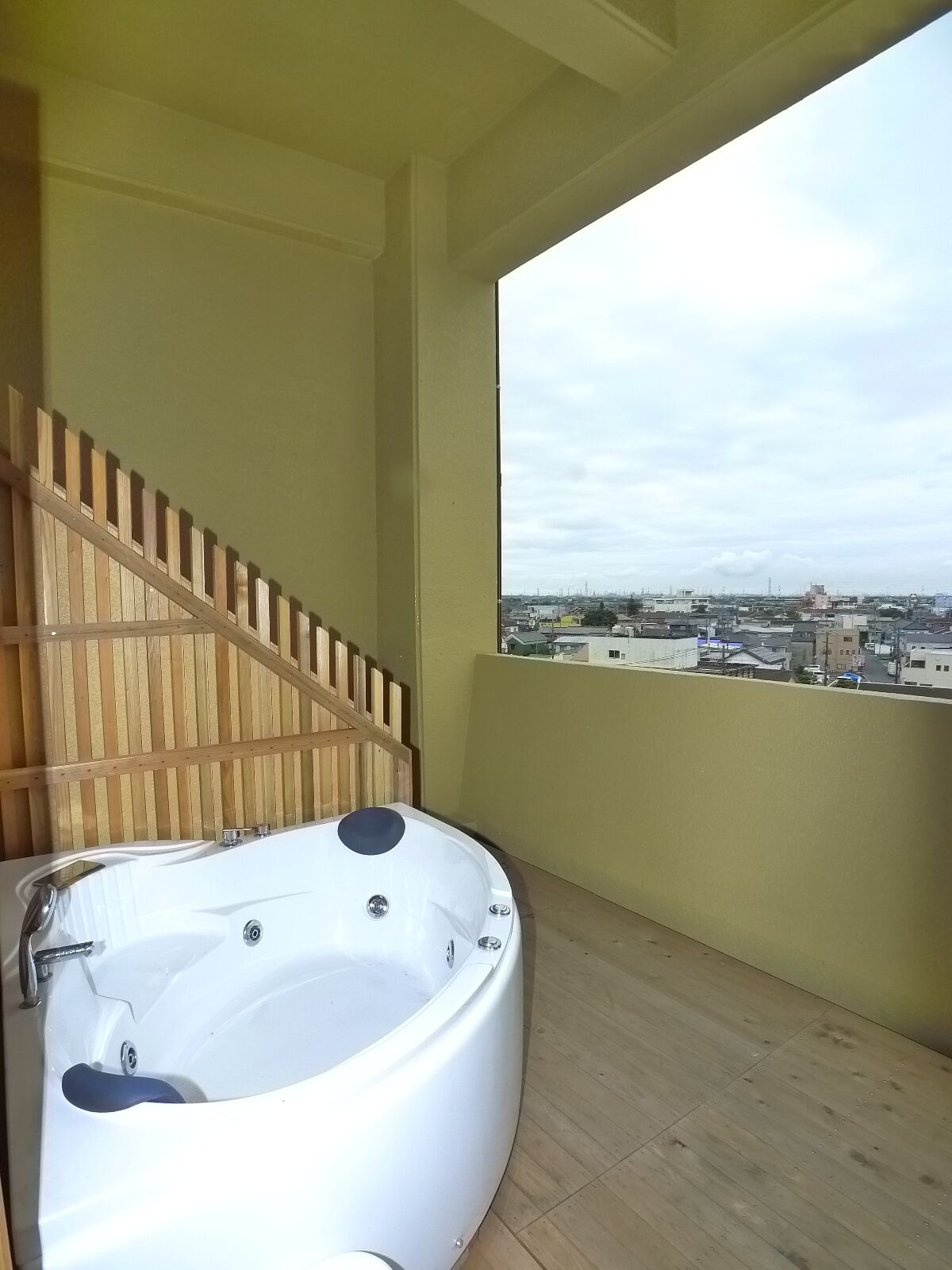 A modern bathroom with a freestanding bathtub, wooden paneling, and a city view through a large window.