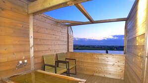 A wooden cabin with a glass-enclosed hot tub and a view of a lake at dusk. - New Makomo Hotel (Itako)