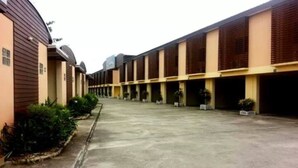 A long corridor with multiple parking bays, a central walkway, and a row of buildings with a uniform architectural style. - PR Resort Hat Yai (Hat Yai)