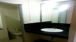 A small bathroom with a toilet, a sink, and a mirror. - PR Resort Hat Yai (Hat Yai)