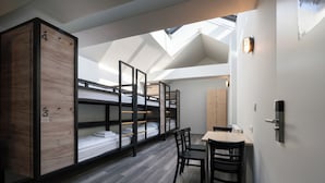 A dormitory room with bunk beds, a skylight, a dining table, and chairs. - a&o Hostel Salzburg Hauptbahnhof (Salzburg)