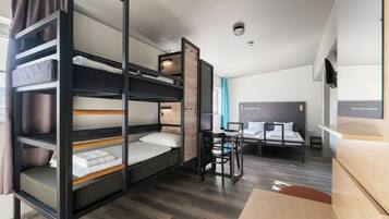 Habitación con literas, un escritorio, una silla, una cama individual y una mesita.