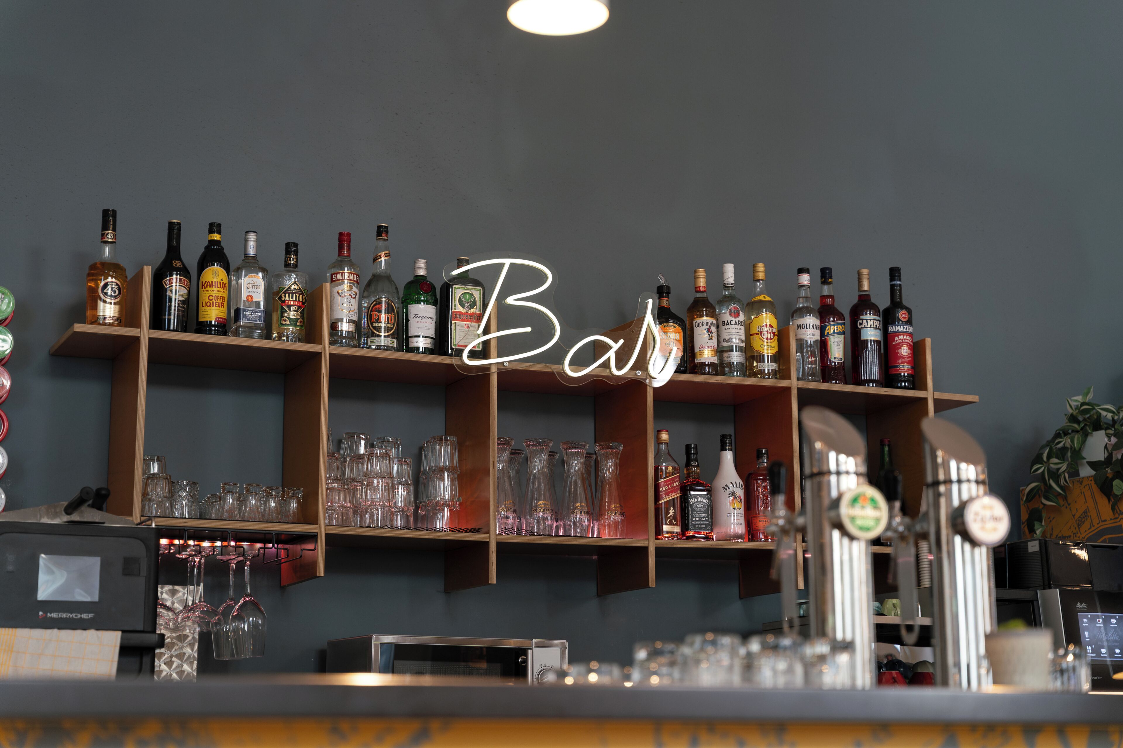 A bar area with shelves of liquor bottles and glasses.