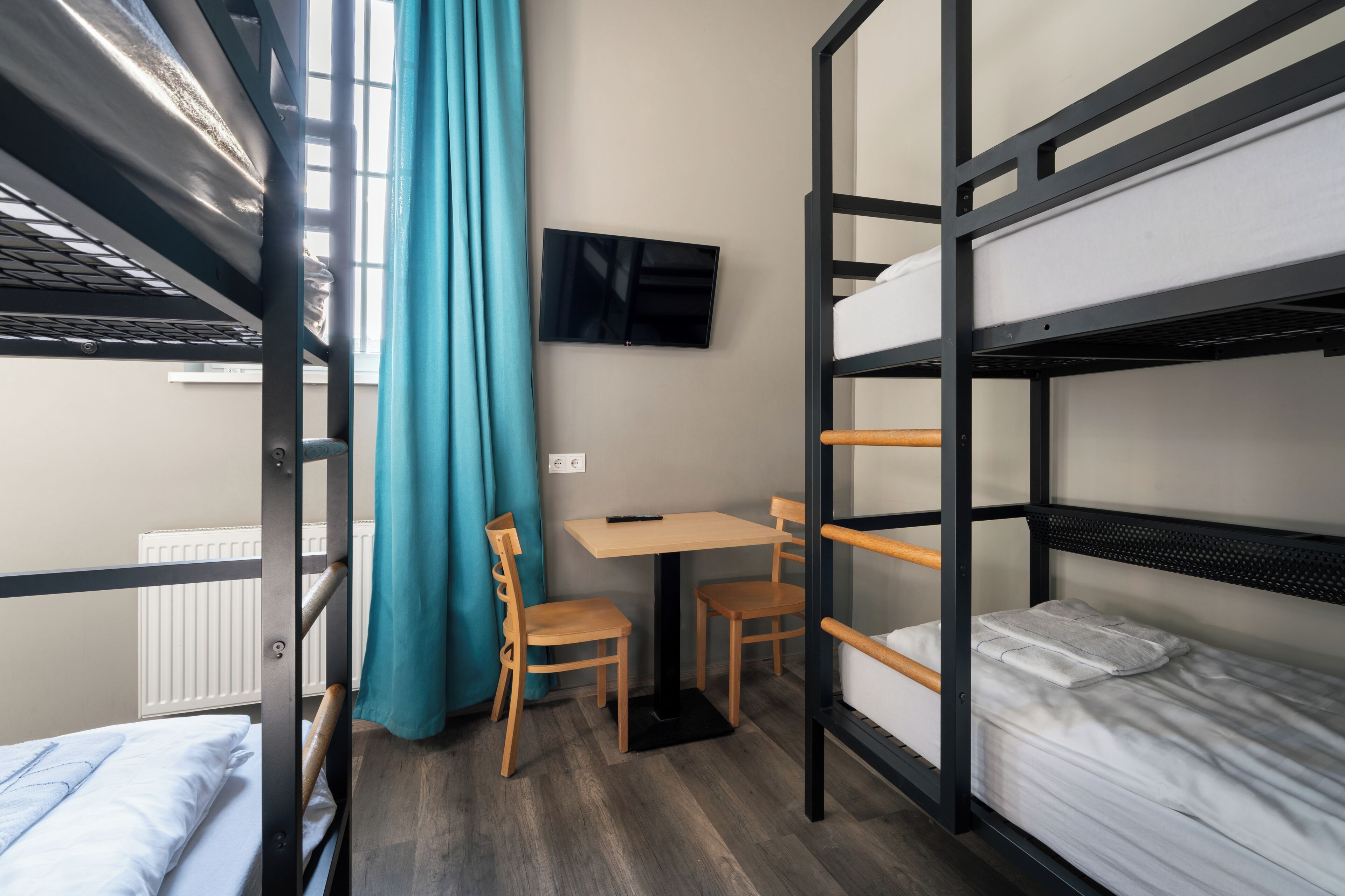 Habitación con literas, escritorio, sillas y televisión.